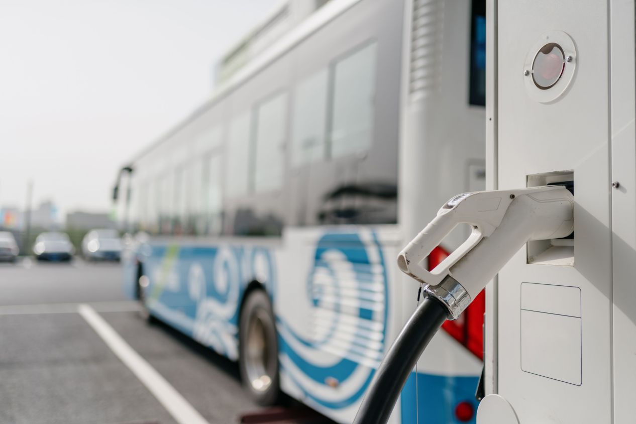 An electric bus is charging at a modern EV charging station, showcasing sustainable public transportation infrastructure with a focus on clean energy solutions.
